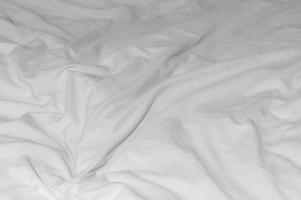 White crumpled or wrinkled bedding sheet or blanket with pattern after guest's use taken in hotel, resort room with copy space, Untidy blanket background texture photo