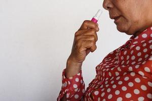 Closeup Asian woman use inhaler to smell  for relieve dizzy or faint symptoms. Concept, health problem, sickness and remedy. Increases freshness, reduces dizziness and stuffy nose. self take care. photo