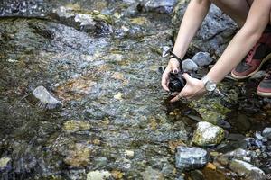 The girl makes a photo or video with a camera from the shore.