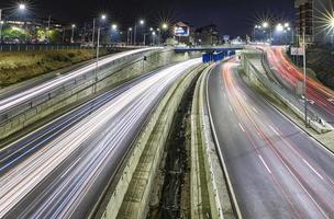 Impresionante carretera de cruce de tráfico nocturno con luces de movimiento de vehículos. foto