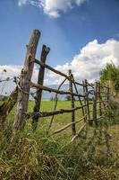 una cerca de madera hecha a mano hecha de varillas delgadas. la antigua valla de troncos de árboles, paisaje rural, fondo de papel pintado de la naturaleza. foto