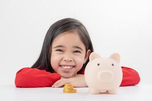 Little Asian girl saving money in a piggy bank, learning about saving, Kid save money for future education. Money, finances, insurance, and people concept photo