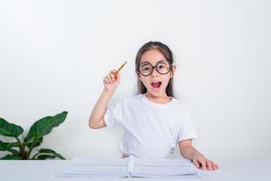 retrato de una pequeña alumna escribiendo en el escritorio en el estudio de una estudiante haciendo pruebas en la escuela primaria. niños escribiendo notas en el aula. concepto de conocimiento educativo foto