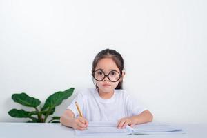 Portrait of little pupil writing at desk in  Student girl study doing test in primary school. Children writing notes in classroom. Education knowledge concept photo