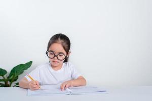 Portrait of little pupil writing at desk in  Student girl study doing test in primary school. Children writing notes in classroom. Education knowledge concept photo