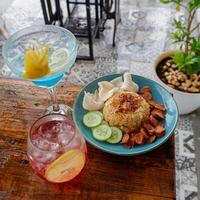 Nasi Goreng Jawa. The popular Indonesian rice dish of fried rice, cooked Javanese style with sweet soy sauce. Accompanied crackers, sausage, cucumber pieces, and soft drink photo