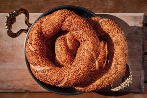 A stack of freshly baked Turkish bagel simit in a copper tray, breakfast snacks in Turkey. Top view of fresh baked goods. photo