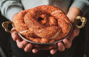 The girl holds in her hands fresh simit in a copper tray, a freshly baked Turkish bagel close-up. breakfast idea photo