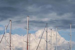 Yacht masts in the harbor against the clouds of a pre-stormy sky, an idea for a background or news about yachting. Holidays on the Mediterranean Sea, a trip on a yacht photo