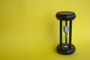 Minute glass isolated on yellow background. Copy space concept photo