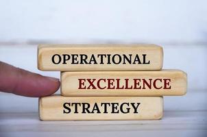 Hand pointing Operational Excellence Strategy text on wooden blocks. Operational excellence and business strategy concept photo