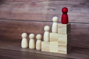 figura roja sobre bloques de madera que lleva a otras figuras al éxito. concepto de liderazgo y cultura empresarial foto