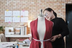 la diseñadora de vestuario asiática madura mide el tamaño de la forma de la marioneta de vestir en un estudio y trabaja con ropa, colección de diseño de moda, sastre boutique profesional, modista pyme emprendedora. foto