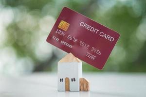 Miniature wood home with red credit card against nature background. Property investment. photo