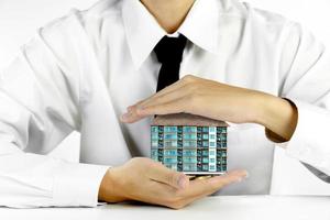businessman hands protecting condominium model with piles of golden coins photo