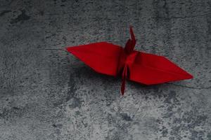 Red paper crane on gray background. Symbol of hope. photo