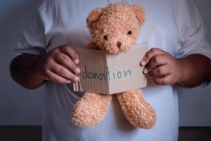 mano masculina que sostiene el oso de peluche para la donación foto