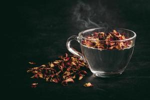 Rose tea in transparent glass on black background photo