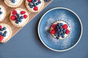 Top view of an assortment of small tarts placed on a cutting board and a blue plate. photo