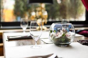 vasos vacíos colocados en vasos de restaurante en el restaurante sobre las flores de la mesa foto
