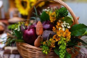 cesta con verduras orgánicas sobre la hierba verde y flores. al aire libre. verduras recién cosechadas. verduras crudas en cesta de mimbre.cesta con verduras y flores foto