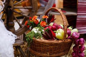 cesta con verduras orgánicas sobre la hierba verde y flores. al aire libre. verduras recién cosechadas. verduras crudas en cesta de mimbre.cesta con verduras y flores foto