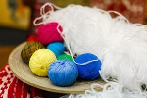 Colorful yarn for knitting in green basket on wooden table on window background Crochet for knitting photo