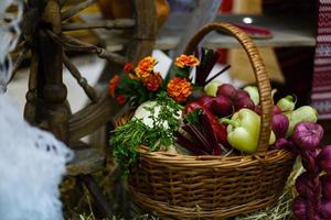 cesta con verduras orgánicas sobre la hierba verde y flores. al aire libre. verduras recién cosechadas. verduras crudas en cesta de mimbre.cesta con verduras y flores foto