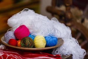 Colorful yarn for knitting in green basket on wooden table on window background Crochet for knitting photo