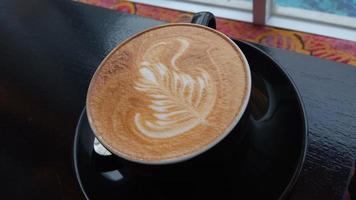 close up shot of capuchino art in a black coffee cup photo