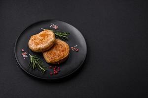 Grilled meatballs with spices and herbs or crepinette on a black plate photo