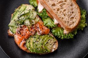 Fresh tasty sandwich with salmon, avocado and sesame and flax seeds photo
