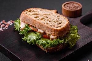 Fresh tasty sandwich with chicken, tomatoes and lettuce on a black plate photo