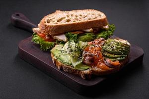 Fresh tasty sandwich with salmon, avocado and sesame and flax seeds photo