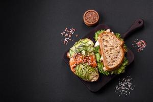 Fresh tasty sandwich with salmon, avocado and sesame and flax seeds photo