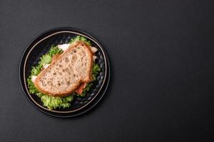 Fresh tasty sandwich with chicken, tomatoes and lettuce on a black plate photo