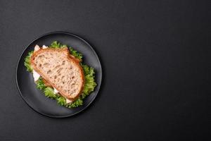 Fresh tasty sandwich with chicken, tomatoes and lettuce on a black plate photo