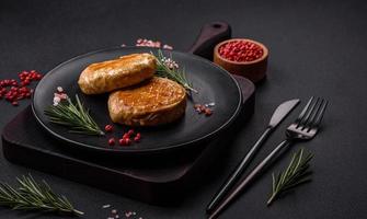 Grilled meatballs with spices and herbs or crepinette on a black plate photo