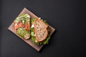 Fresh tasty sandwich with salmon, avocado and sesame and flax seeds photo