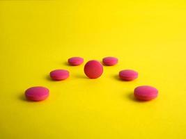 Drug. Round red tablets on a yellow background. Medicine, pharmaceuticals photo