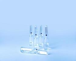 closed glass medical ampoules lie on a blue background. vessel for drugs photo