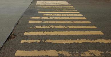 Damaged old yellow zebra cross on public road. Road sign for people crossing the road. Urban city road image. photo