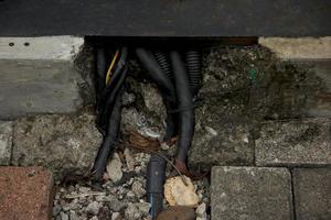 cable industrial negro con conchas de piedra dañadas. foto de la tubería al aire libre de la vía pública.