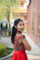 chica inteligente en vestido de color rojo estilo chiness año nuevo en cultura y fondo de templo chino público foto