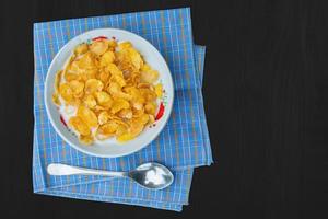 corn flakes with milk on black wood table top view photo