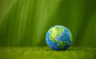 World Earth Day Concept. Green Energy, ESG, Renewable and Sustainable Resources. Environmental Care. Globe against on Green Grass and Leaf. Side View photo