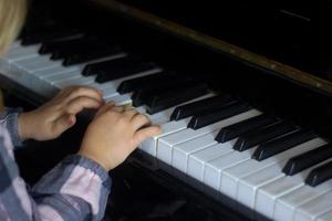 niña pequeña toca el piano, los niños manos en el teclado del piano de cerca, educación en el hogar, educación musical. niño talentoso en crecimiento. rutina diaria para niños pequeños, vista lateral de las manos y el piano de los niños