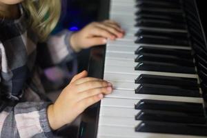niña pequeña toca el piano, los niños manos en el teclado del piano de cerca, educación en el hogar, educación musical. niño talentoso en crecimiento. rutina diaria para niños pequeños, vista lateral de las manos y el piano de los niños.