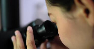 Close up shot, Selective focus eye of professional female veterinarian looking through microscope in laboratory, Smart scientist doing research for biology and medical science of animals video