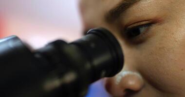 Nahaufnahme, selektiver Fokus Auge einer professionellen Tierärztin, die im Labor durch das Mikroskop schaut, kluge Wissenschaftlerin, die für Biologie und Tiermedizin forscht video